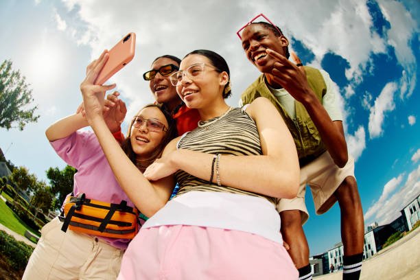 Wide angle shot of Gen Z group of friends using a smartphone together.
