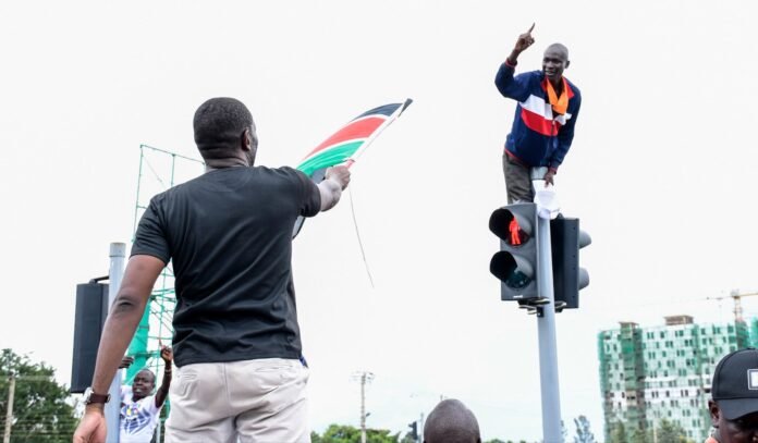 Edwin Sifuna raises the Kenyan flag with one finger in the air, signaling defiance and growing momentum during the charged rally in Kisumu.