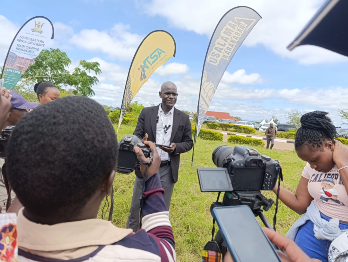 NTSA Director General Nashon Kondiwa addressing a media briefing about the launch of the electronic motor vehicle registration certificate. He stands next to a presentation slide detailing how the e-Logbook will reduce fraud and eliminate the need for physical documents starting June 10, 2026