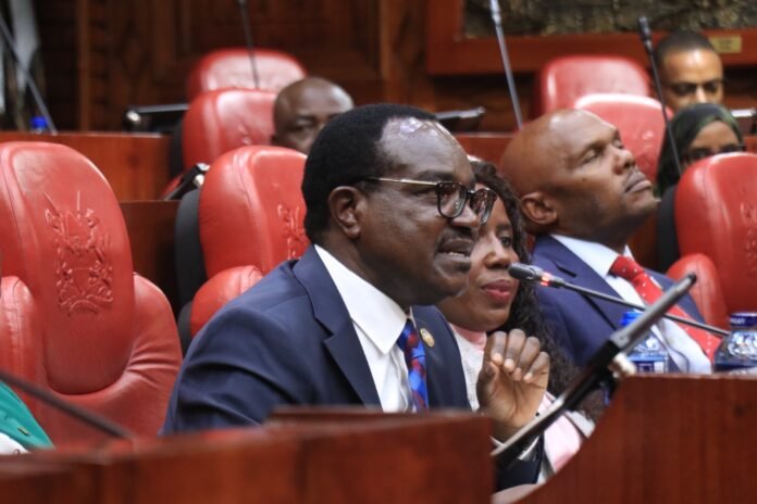 CS Julius Ogamba. Education CS Julius Migos Ogamba has told MPs that chronic underfunding and delayed Treasury releases, not ministry inefficiency, are behind the financial crisis affecting schools, TVETs and universities.